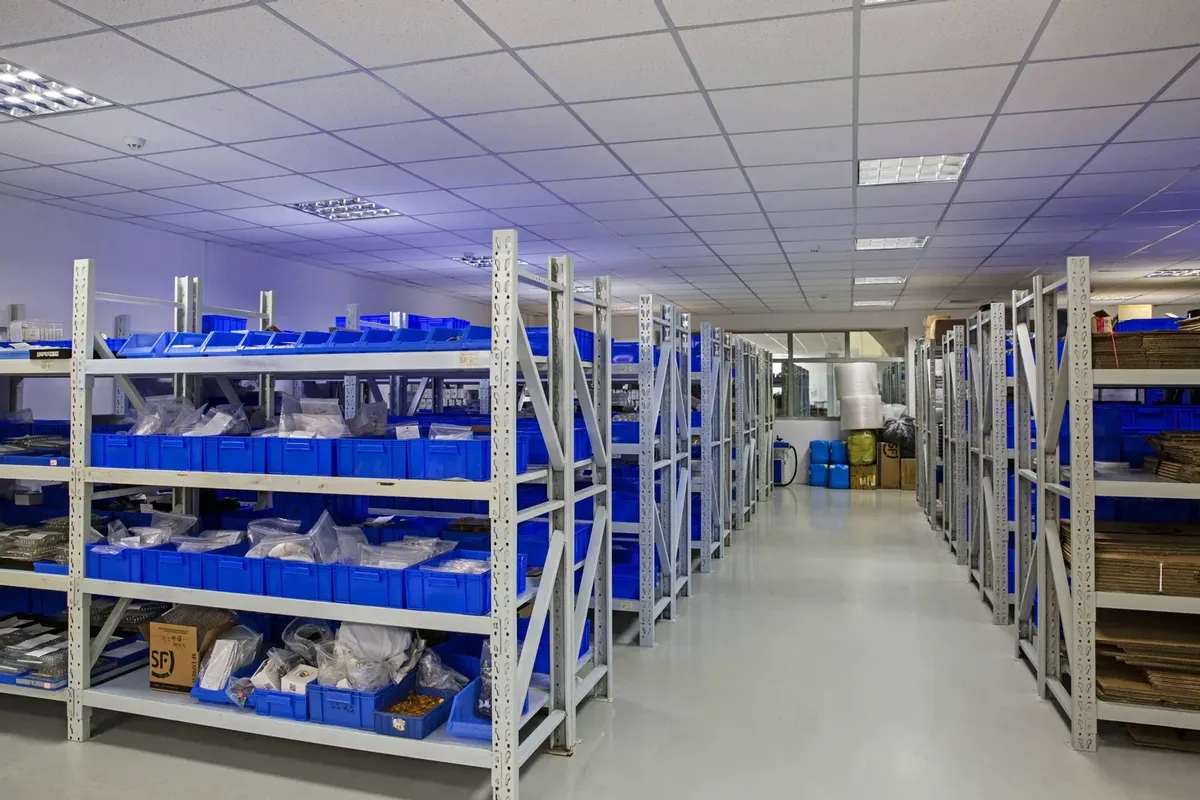 Warehouse racking with blue bins holding laser cutting nozzles, protective windows and ceramic rings, sorted by size